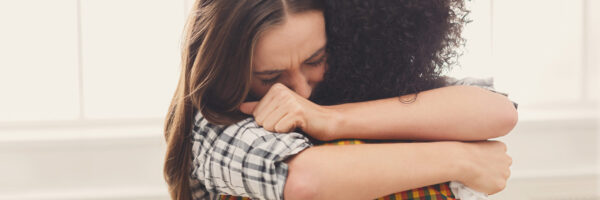 Woman hugging her depressed friend at home, closeup. Young girl supporting her crying girlfriend. Friendship consoling and care, copy space