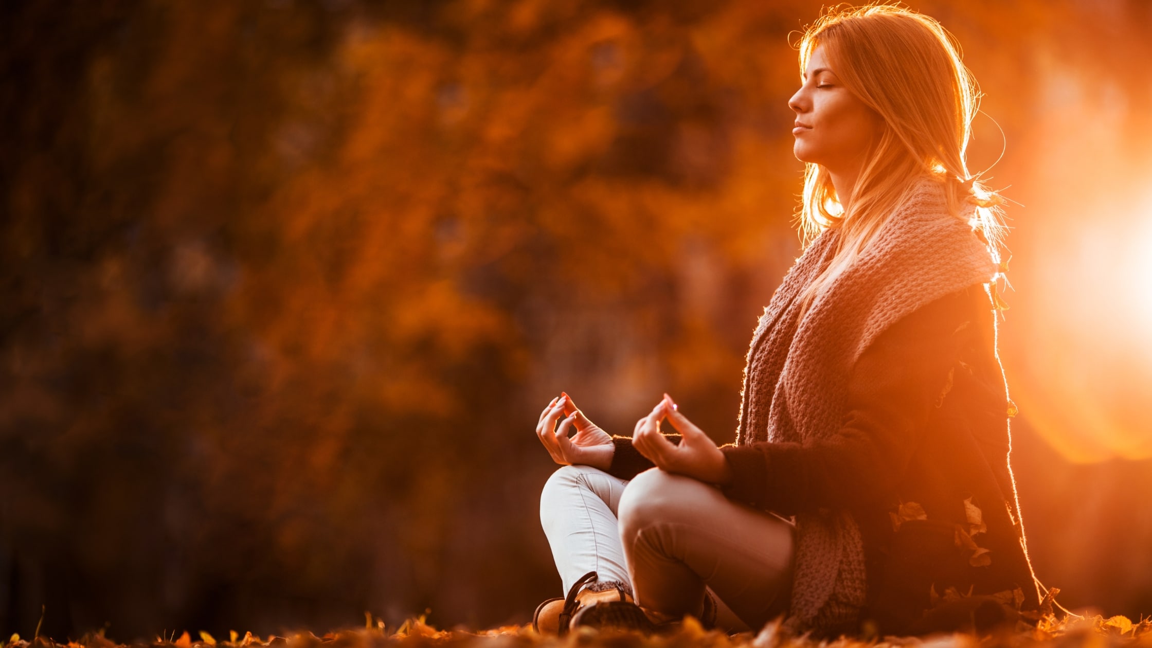 Person meditating in autumn sunlight