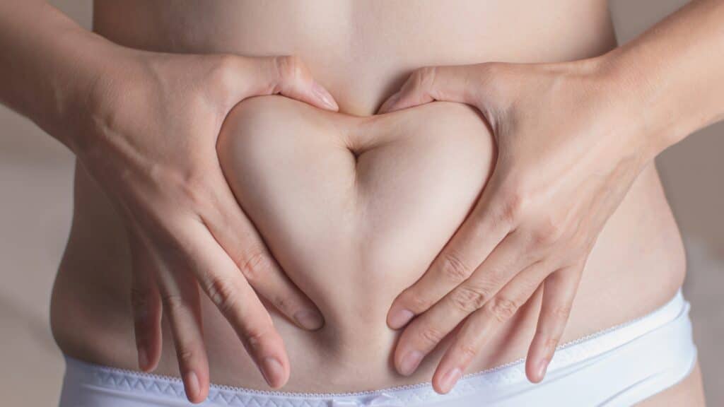 Hands forming a heart shape on stomach.